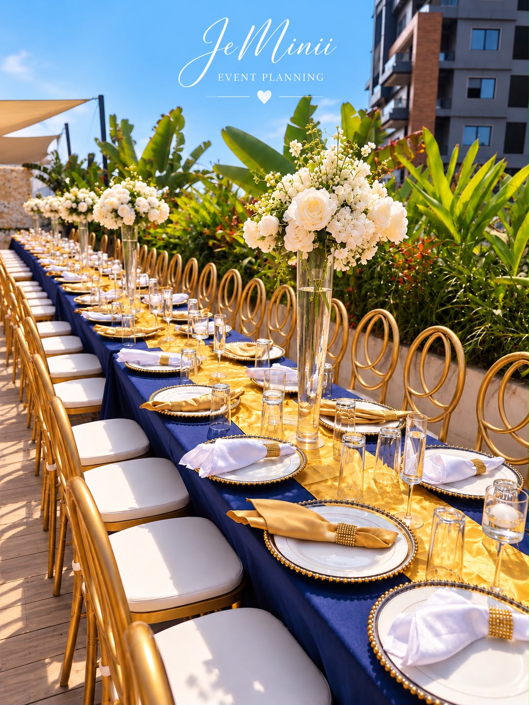 Long wedding banquet table with navy linen, gold place settings and tall white floral arrangements, styled by Jeminii Event Styling